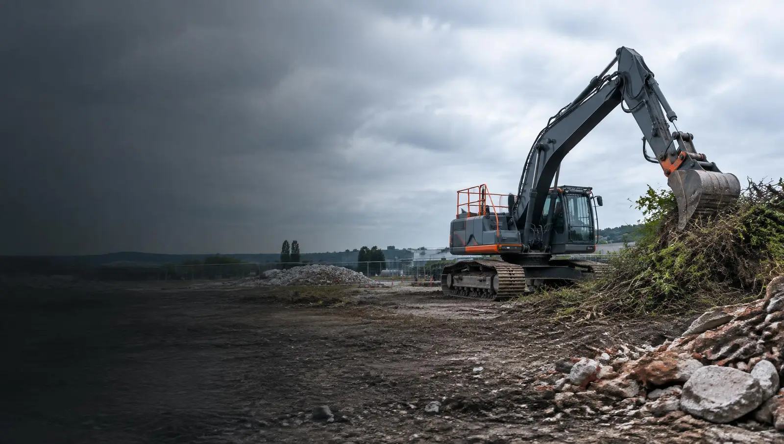Excavator clearing vegetation and rubble from a development site